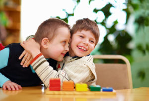 A picture of two boys hugging and playing with a puzzle