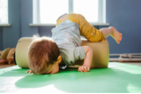 a child faceplanting on the soft cushion while his legs are still on the climber