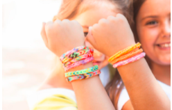 two young girl holding up their wrist to show off their bracelet