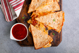 a picture of quesadillas on a wooden cutting board with red dipping sauce 