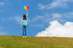 A child standing in the middle of the field holding a spinner in the air